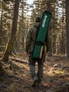 Hunter walking through a forest trail carrying a large capacity recurve bow case with shoulder strap